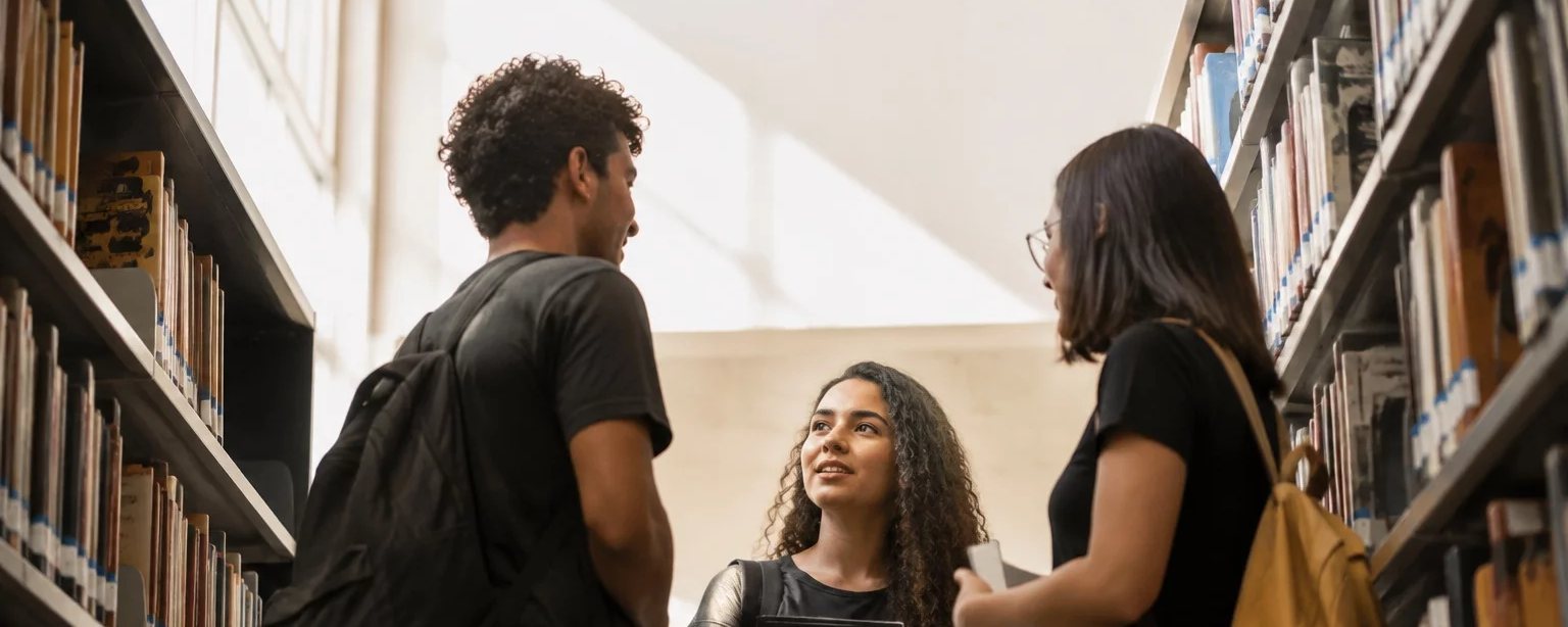 Três participantes conversando na ponta de uma mesa comprida